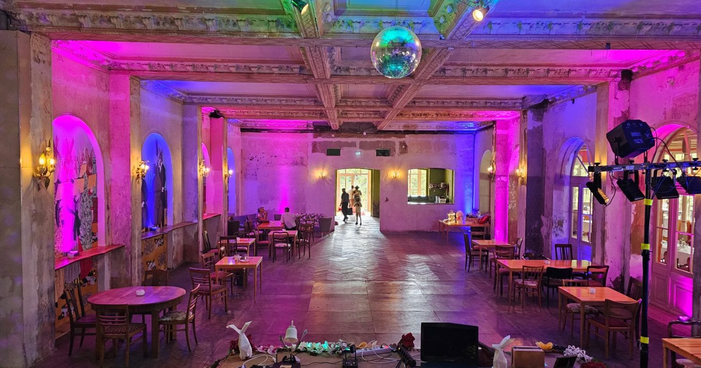 Festsaal mit Ambientebeleuchtung und Tischanordnung für eine Veranstaltung.