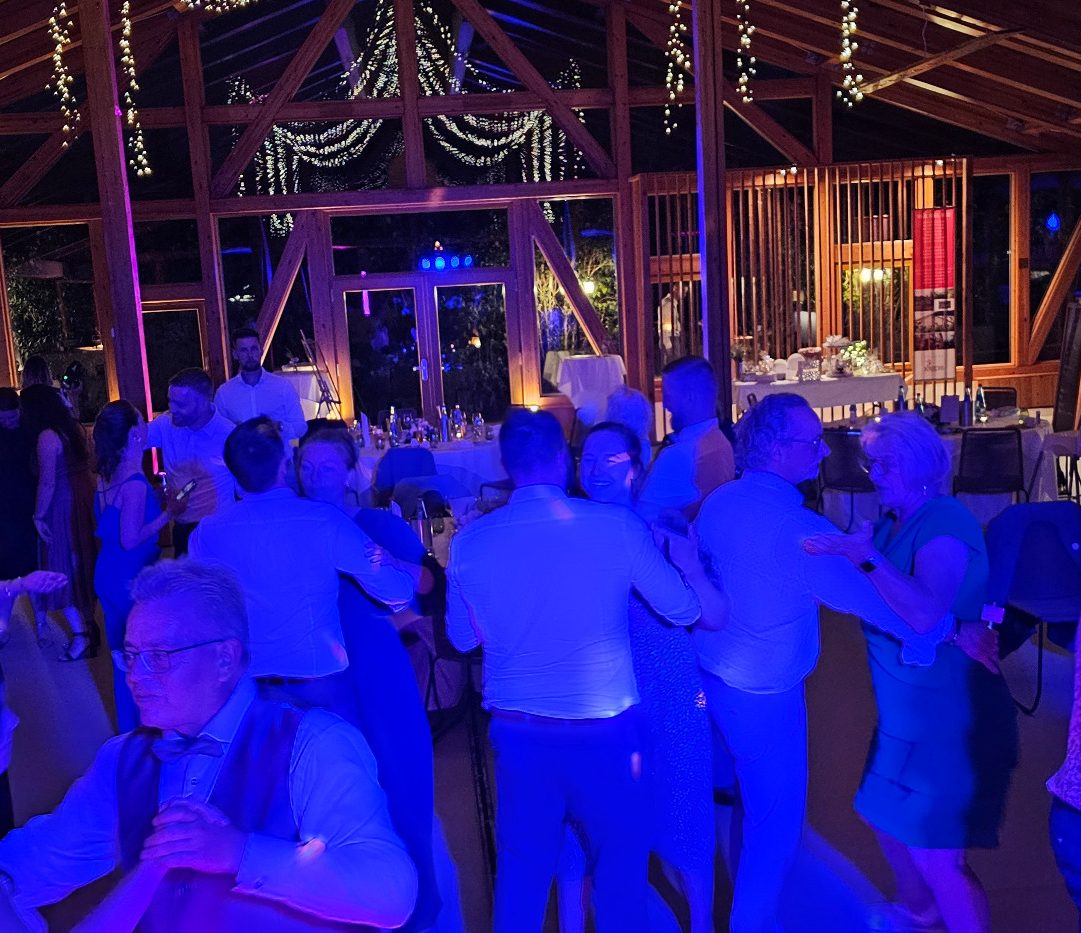 Tanzende Menschen in einem festlichen Ambiente, blau beleuchteten Raum mit Dekoration.