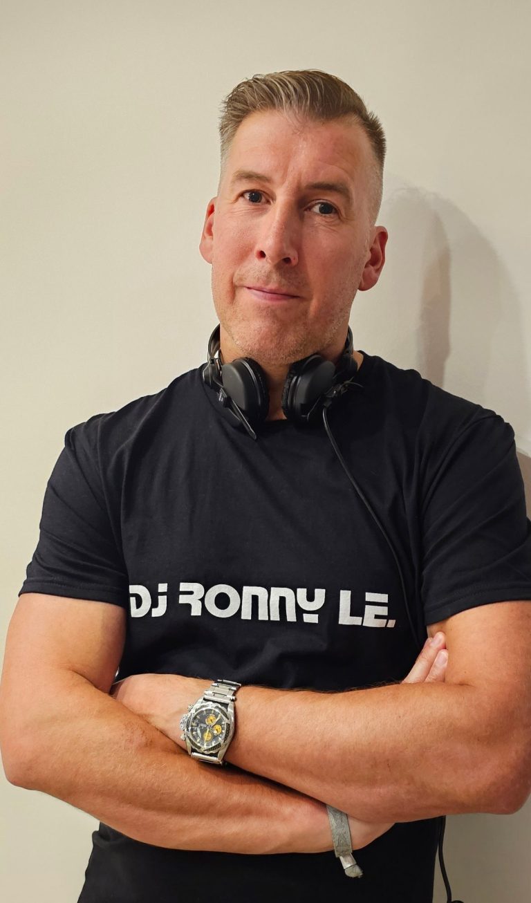 Mann mit Kopfhörern, T-Shirt mit „DJ RONNY LE“, verschränkt die Arme.