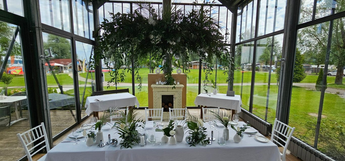 Elegant gedeckter Tisch mit Blumendekoration in einem lichtdurchfluteten Raum.