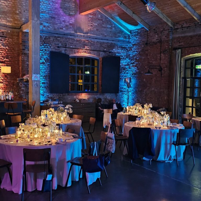 Elegante Veranstaltung mit festlich dekorierten Tischen in einem beleuchteten Raum.