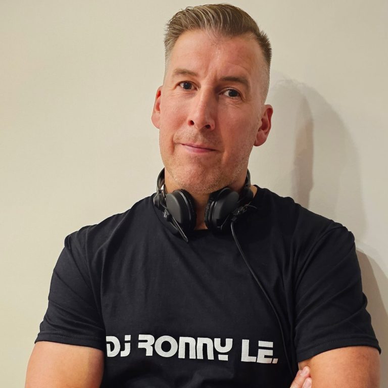 DJ Ronny LE. Mann mit Kopfhörern, T-Shirt mit „DJ RONNY LE“, verschränkt die Arme.