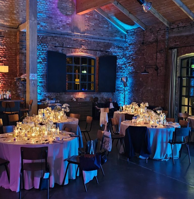 Elegante Veranstaltung mit festlich dekorierten Tischen in einem beleuchteten Raum.