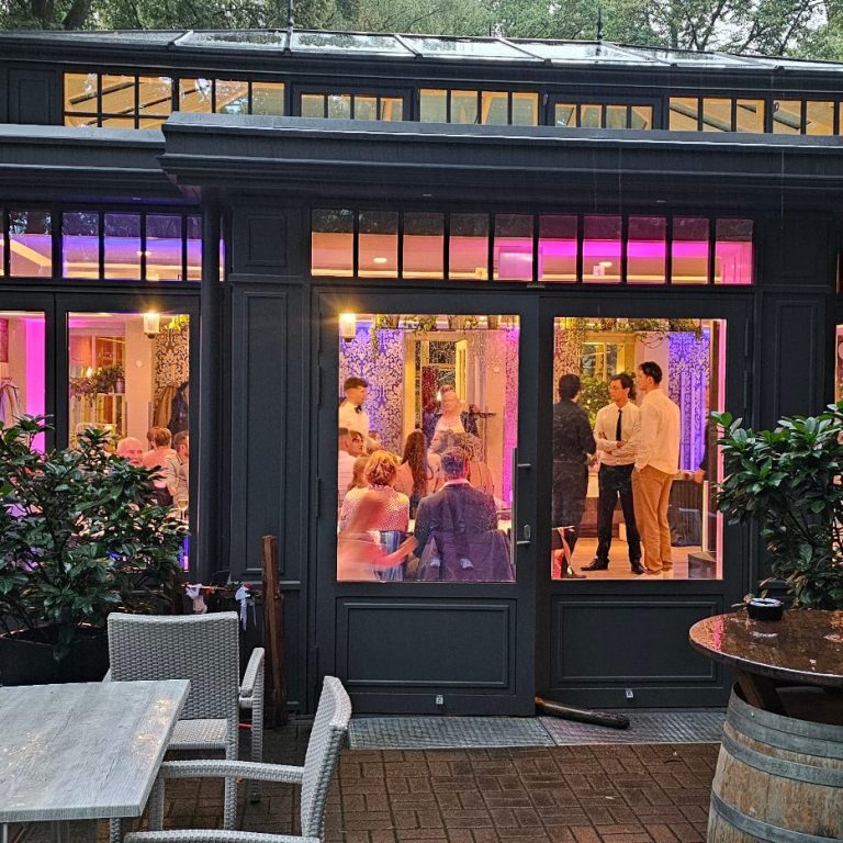 Schöne Ambiente einer Hochzeit mit Uplights und Gästen beim Feiern.